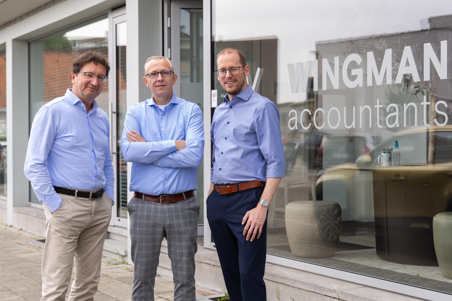 Drie accountants van Wingman Accountants voor het kantoor met het Wingman Accountants-logo op het raam